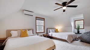 A bedroom with two beds, a ceiling fan, and a large window.