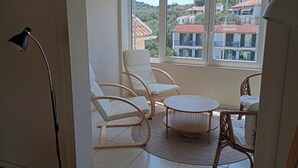 A room with a large window, white walls, and a round table with chairs.