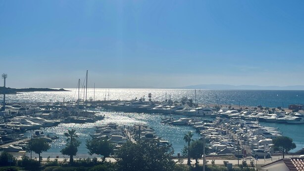 A marina with numerous boats docked, a clear sky, and a distant shoreline. - Exclusive Penthouse Apt at Glyfada Marina &Beach, 2 min walk to shopping, dining (Glifada)
