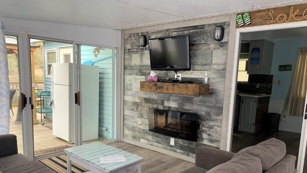Ein Wohnzimmer mit Kamin, Fernseher und einer Schiebetür zu einem Außenbereich.