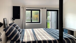 Ein Schlafzimmer mit einem Bett, einem Fenster und einer Tür, die zu einem Außenbereich führt.