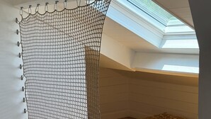 A dormitory room with a skylight, a bed with patterned bedding, and a white wall. - Villa Sunset 500 meters Ocean (Seignosse)