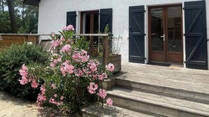 A two-story building with a white exterior, black shutters, and a wooden deck leading to the entrance. - Villa Sunset 500 meters Ocean (Seignosse)