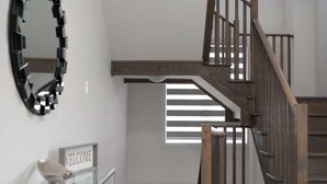 Una escala moderna amb barana de fusta i barana de vidre al replà.