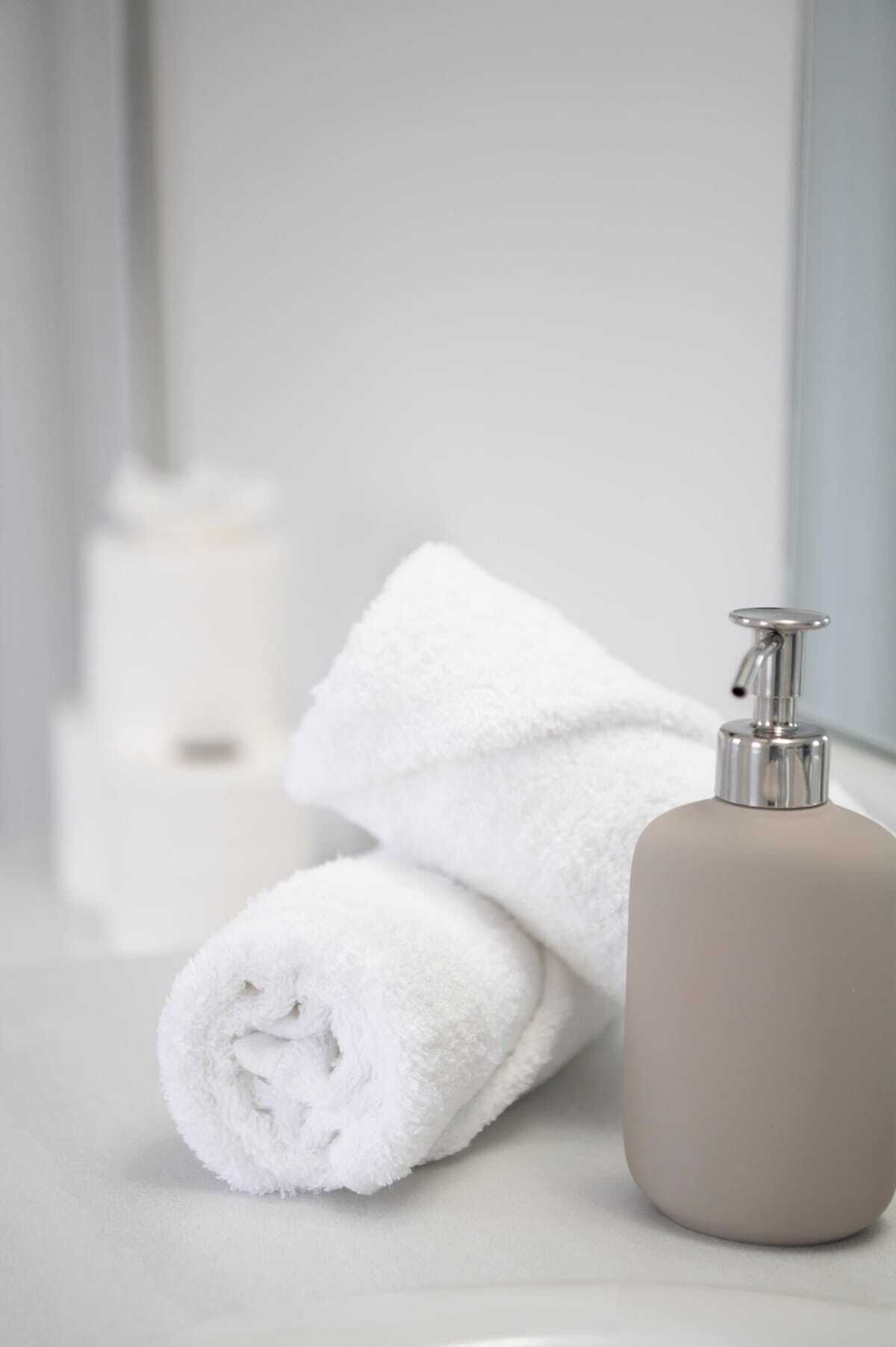 A bathroom with a white towel and a beige bottle of lotion.