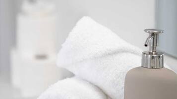 A bathroom with a white towel and a beige bottle of lotion.
