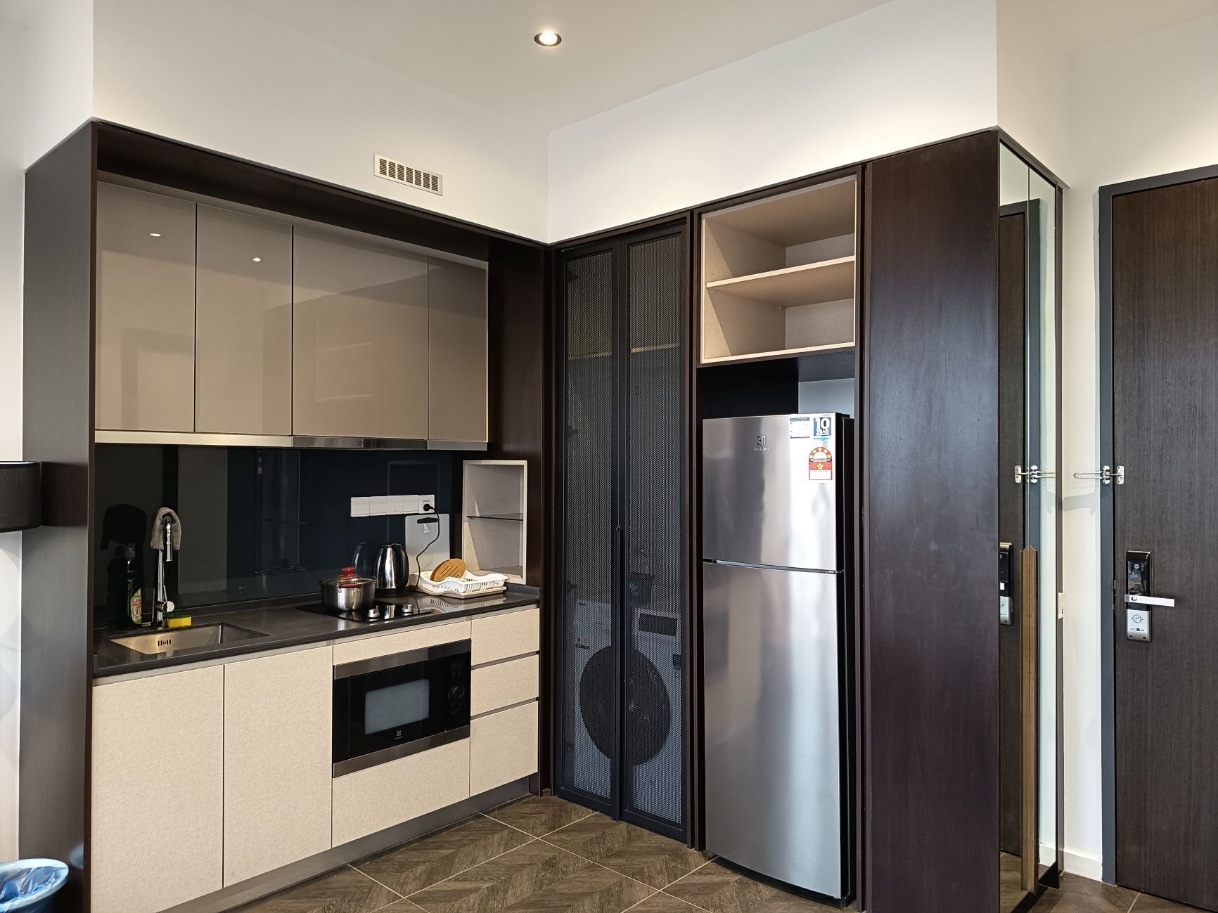 A modern kitchen with a built-in oven, a stainless steel refrigerator, and a large window.