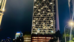 A tall, modern building with a geometric facade and illuminated signage. - Scarletz KLCC By Arman (Kuala Lumpur)