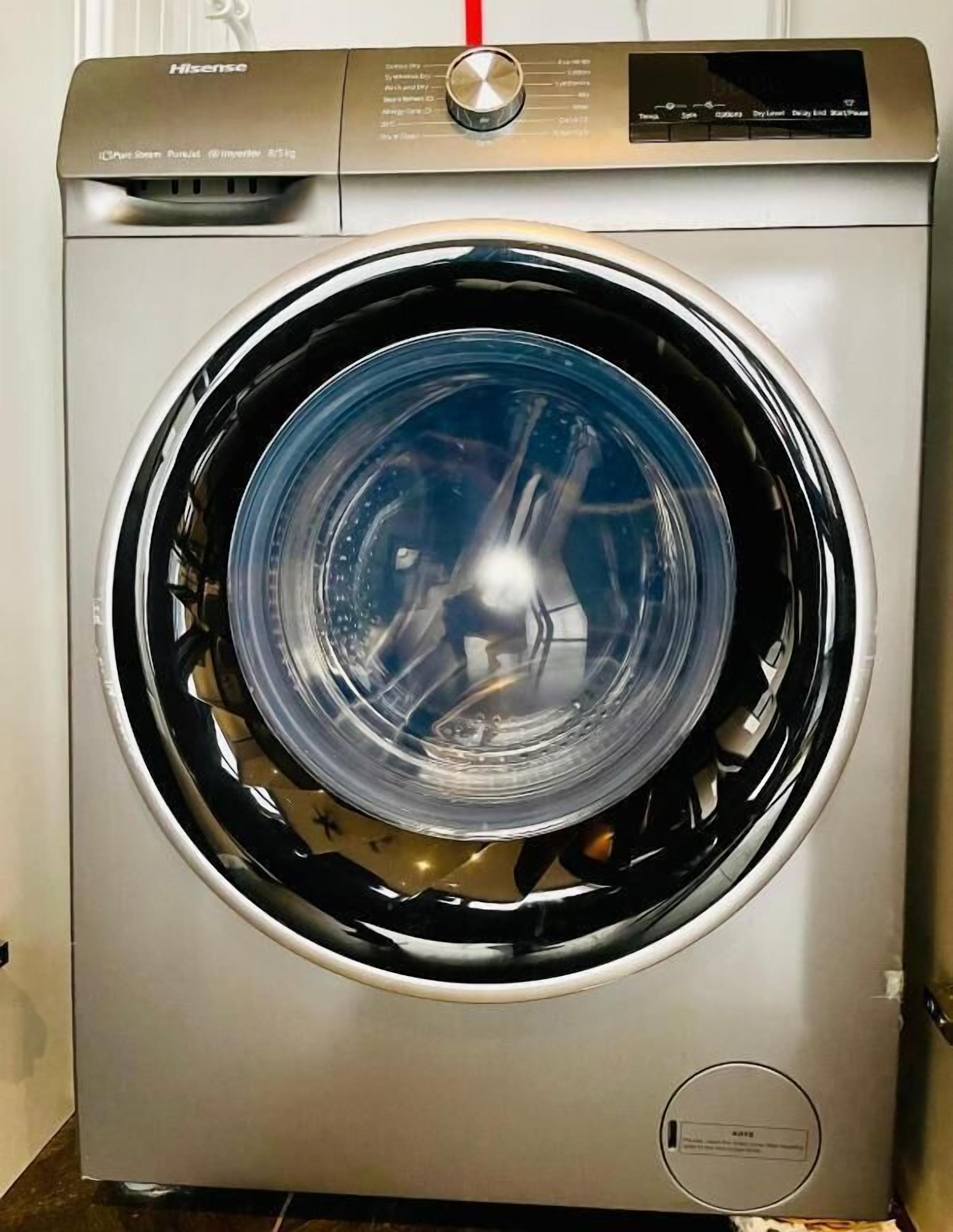 A front view of a front-loading washing machine with a control panel and a transparent door.