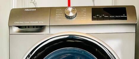 A front view of a front-loading washing machine with a control panel and a transparent door.