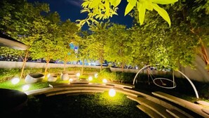 A nighttime outdoor area with a pathway, seating areas, and trees. - Scarletz KLCC By Arman (Kuala Lumpur)