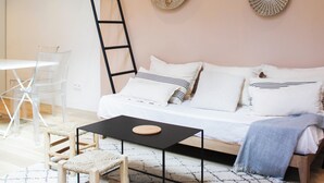 Un salon moderne avec un canapé blanc, une table basse noire et une chaise en bois. Des œuvres d’art décoratives sont accrochées au mur au-dessus du canapé.