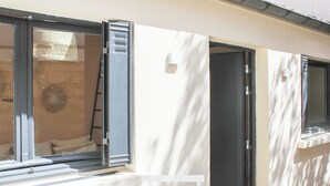 Un couloir bordé d’une série de portes et de fenêtres, dont certaines sont équipées de stores, qui donnent sur des pièces individuelles.