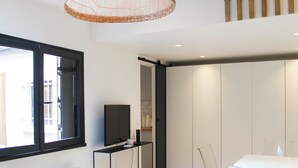 Un espace de vie moderne comprenant un téléviseur posé sur un meuble, une table à manger avec des chaises et une grande fenêtre.