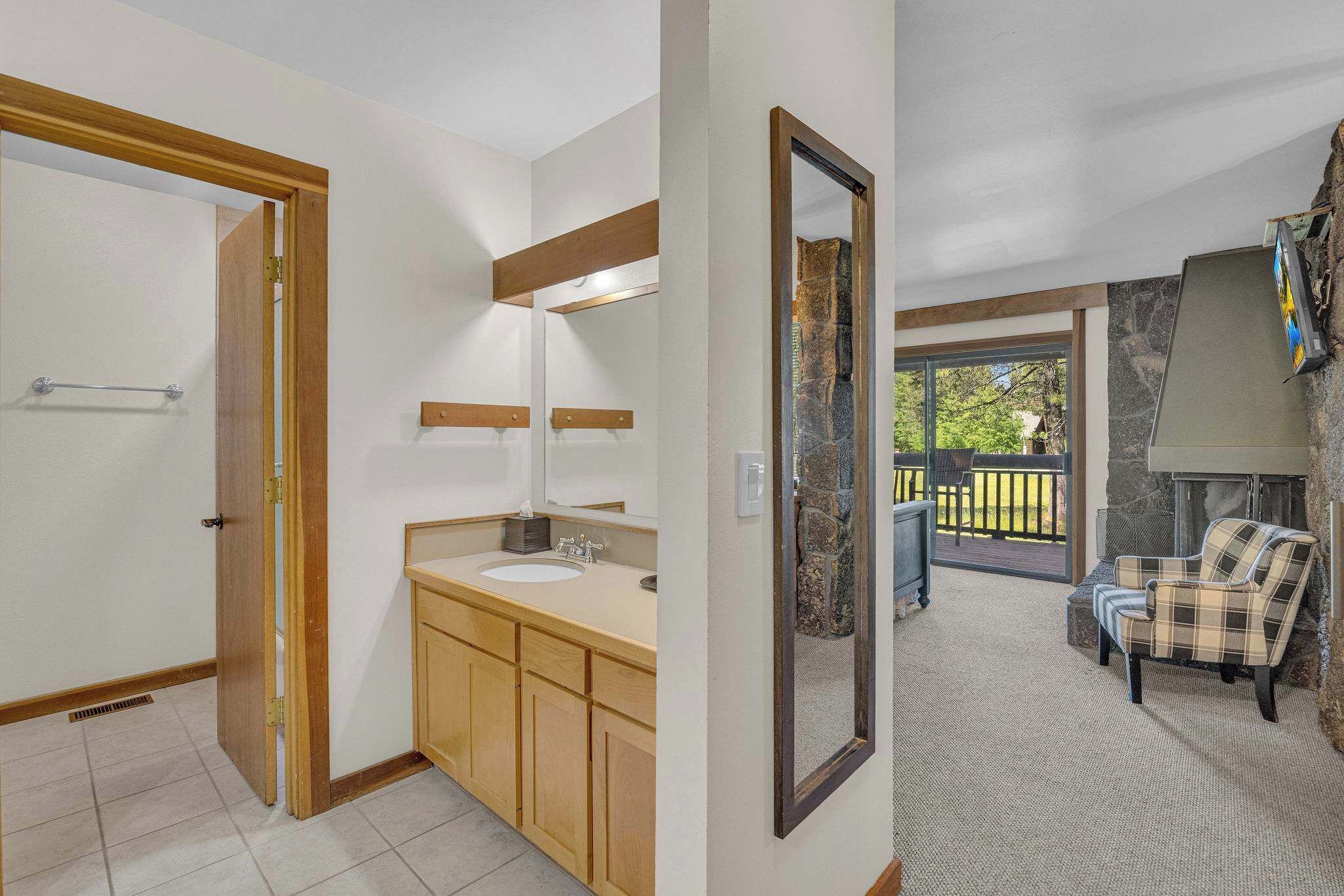 Ett badrum med ett handfat i trä, en stor spegel och utsikt över en balkong med en eldstad i sten.