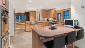 A modern kitchen with granite countertops, wooden cabinets, and a built-in island with bar stools.