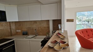 A modern kitchen with white cabinets, a built-in oven, and a wooden countertop with bowls. - Beautiful sea view, beach 100m away. All comforts. As new (Menton)