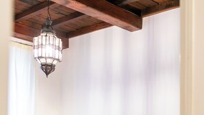 A bedroom with a bed, a hanging light fixture, and a window with curtains. - InCentrum    (Rome)