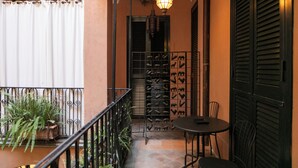 A balcony with a wrought iron railing, a table and chairs, potted plants, and a decorative light fixture. - InCentrum    (Rome)
