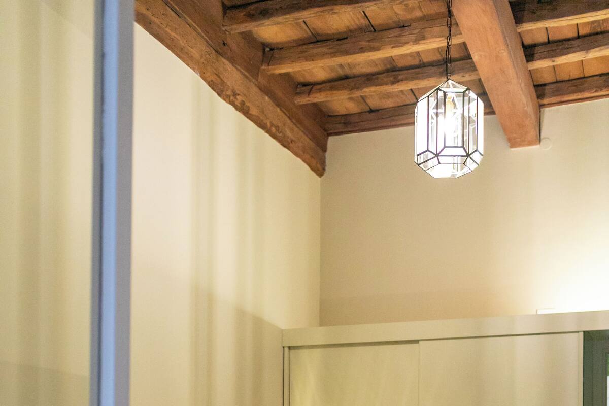 Une chambre à coucher avec un lit, un plafond en bois et un luminaire suspendu.