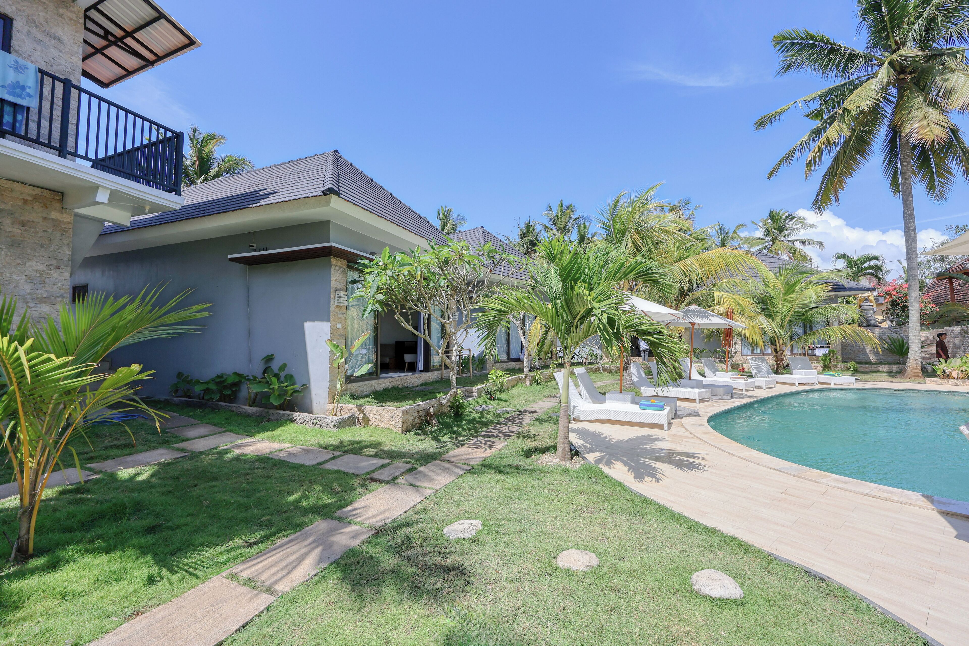 A modern house with a swimming pool, surrounded by palm trees and a well-maintained lawn.