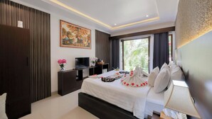 Habitación de hotel moderna con una cama grande, un televisor de pantalla plana, un cuadro y vistas a zonas verdes por la ventana.