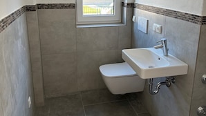 A small bathroom with a window, a sink, and a toilet. - Top modern vacation home family friendly! (Brunnthal)