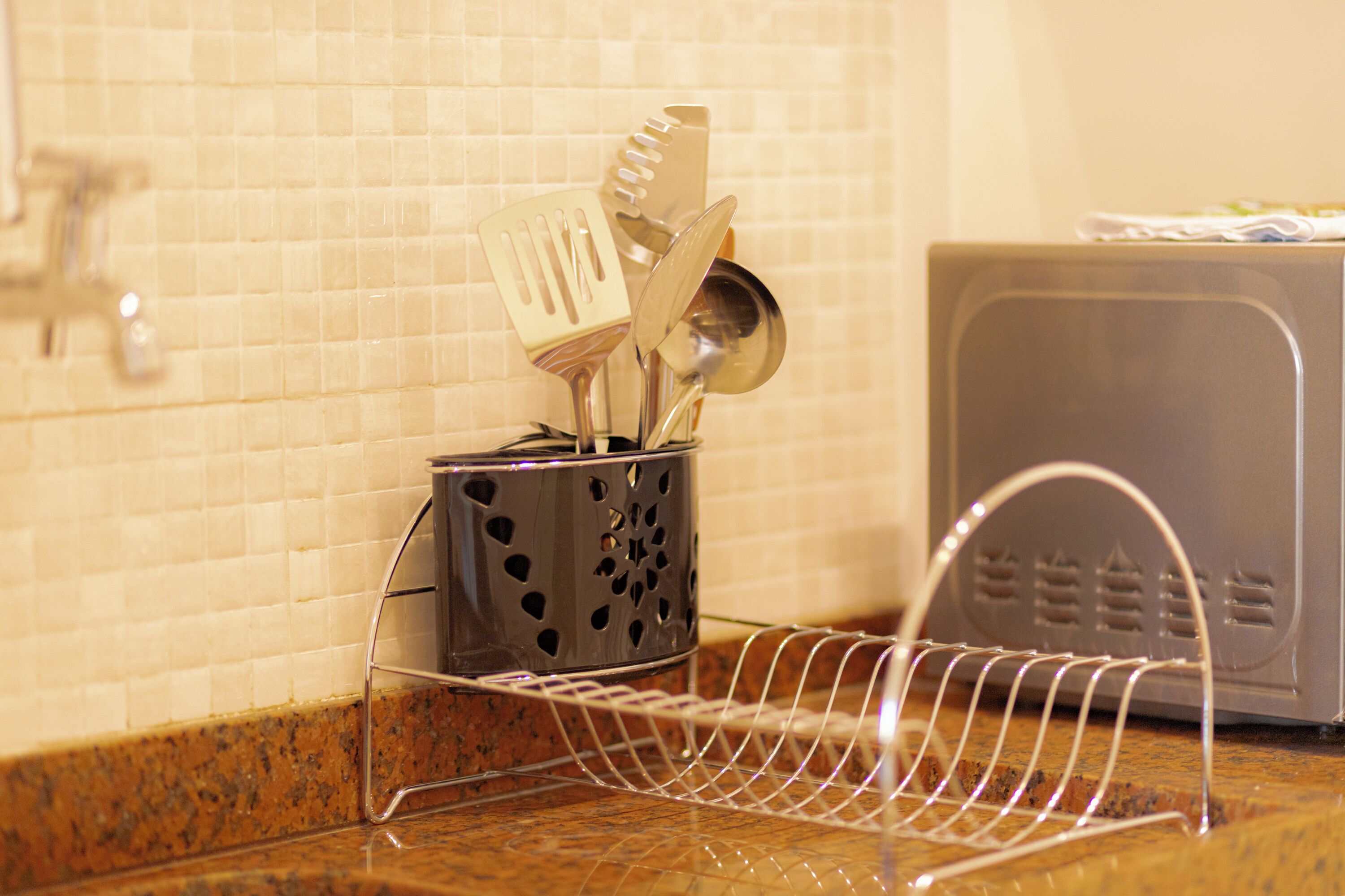 A kitchen area with a utensil holder containing a spatula, a ladle, and a spoon.