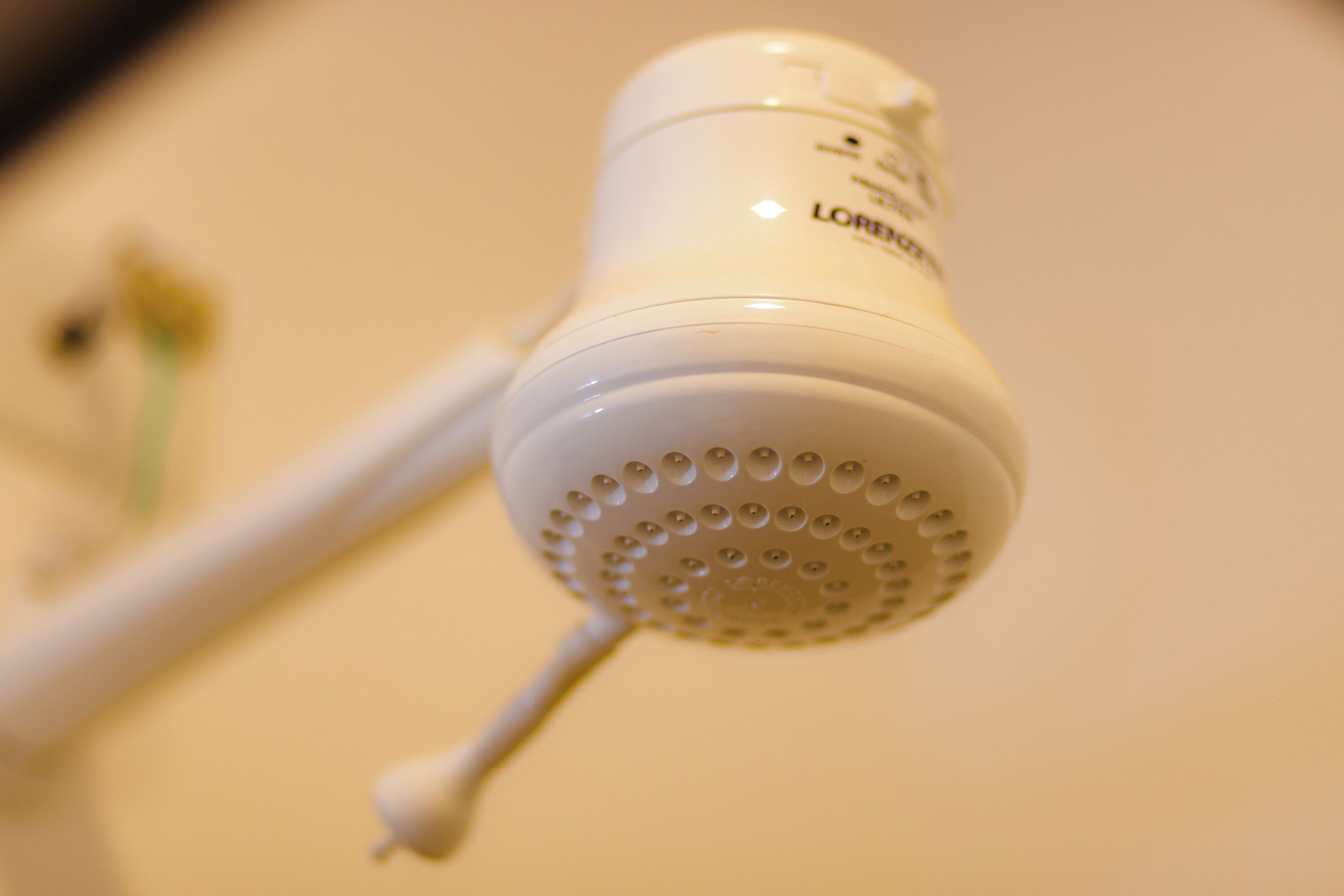 A white showerhead with a circular pattern of holes and a control knob.