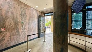 Un vestíbulo de mármol con una recepción, una barrera de seguridad y una columna grande.