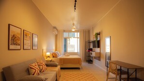Una habitación de hotel moderna con sofá, cama, mesa de comedor y televisor.
