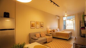 Una habitación de hotel moderna con sofá, cama, mesa de comedor y zona de cocina.