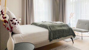 Une chambre à coucher moderne avec un lit, une table de chevet, une chaise et un vase rempli de fleurs.