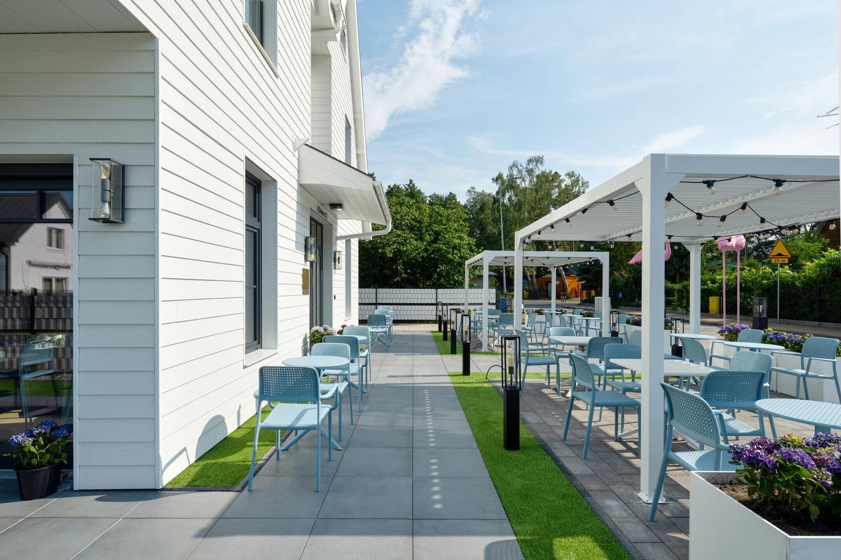 A patio area with outdoor seating, a pathway, and a white building.
