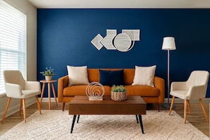 A living room with a blue accent wall, a sofa, two armchairs, a coffee table, and a floor lamp. - FIFA 2026 - 2BR Heights! 20min to NRG Stadium+Pool (Houston)