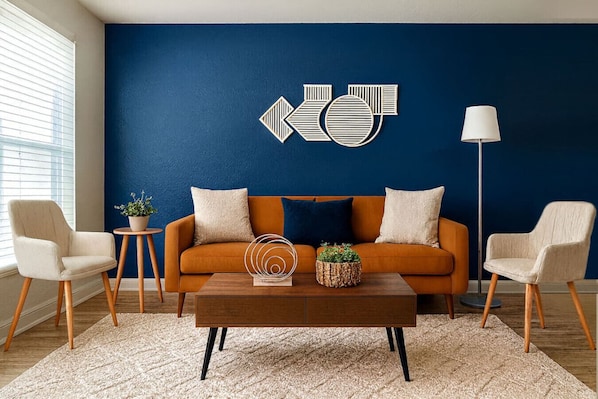 Un salon avec un mur d’accent bleu, un canapé, deux fauteuils, une table basse et un lampadaire.