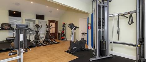 Un gimnasio con diversos equipos de ejercicio, incluyendo cintas de correr, elípticas y estaciones de levantamiento de pesas.