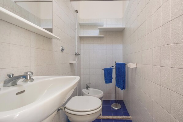 Une salle de bain équipée d’un lavabo, de toilettes, d’un bidet et d’un porte-serviettes avec des serviettes bleues.