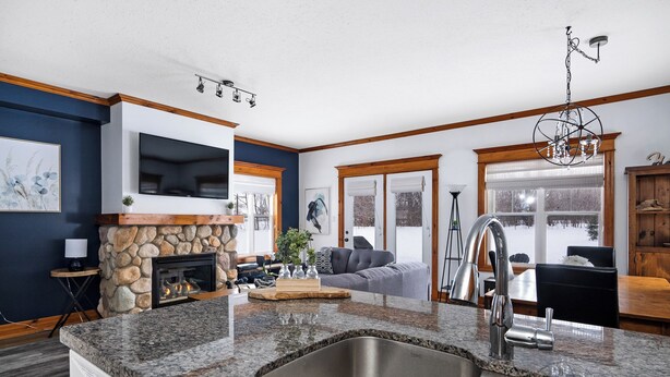 A modern kitchen with granite countertops, a stainless steel sink, and a stone fireplace. - Snowbridge (Blue Mountains)