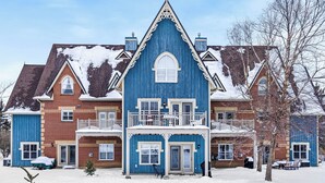 A large, multi-story building with a prominent central tower, multiple balconies, and a snow-covered roof. - Snowbridge (Blue Mountains)