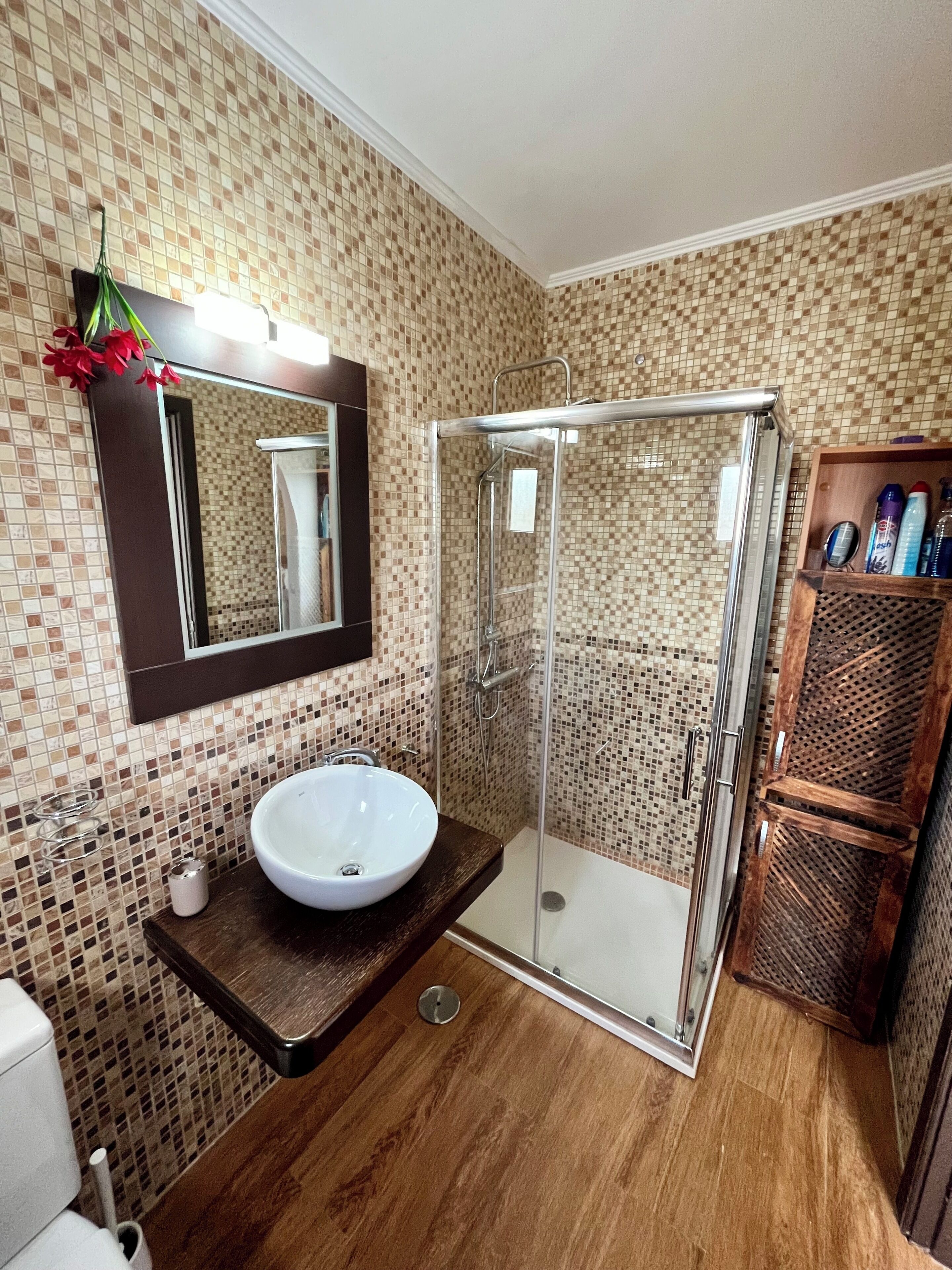 Un baño con ducha de vidrio, un lavamanos blanco y un espejo encima.