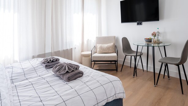A hotel room with a bed, a TV, a small table with chairs, and a window with curtains. - Apartment in Koblenz Near Deutsches Eck (Koblenz)