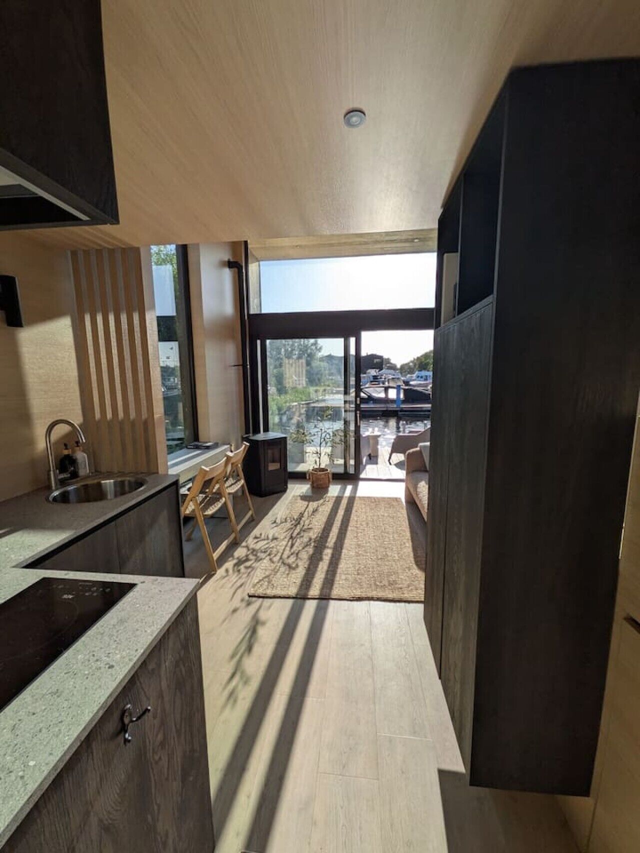 Una cocina moderna con estufa integrada, un lavamanos y una ventana con vista a un balcón.