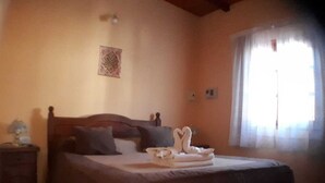 Een slaapkamer met een bed, een nachtkastje, decoratie aan de muur en een raam met gordijnen.