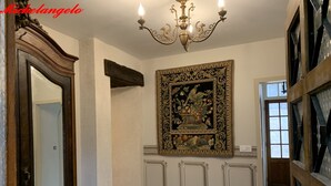 A hallway with a chandelier, a large ornate painting, and a tiled floor. - Michelangelo at our 'Clos Lussault' near Amboise in the Loire Valley (Lussault-sur-Loire)