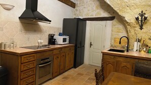 A kitchen with wooden cabinets, a black range hood, a white microwave, and a black refrigerator. - Michelangelo at our 'Clos Lussault' near Amboise in the Loire Valley (Lussault-sur-Loire)