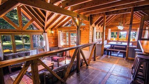 A spacious wooden cabin with a high ceiling, large windows, and a cozy seating area.