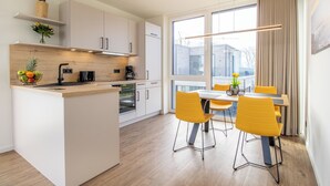 A modern kitchen with a central island, yellow chairs, and a dining table.