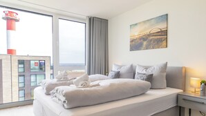A modern hotel room with a large bed, a nightstand, a lamp, and a painting on the wall.