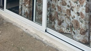 A sliding glass door with floral curtains, a white frame, and a small picture above the door.
